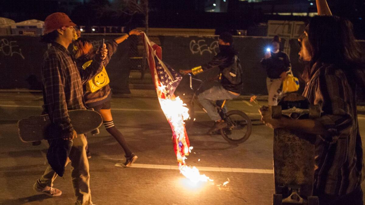 A demonstrator drags a burning American flag through the streets during a march through the streets in protest against President-elect Donald Trump in Oakland, CA. on November 10.