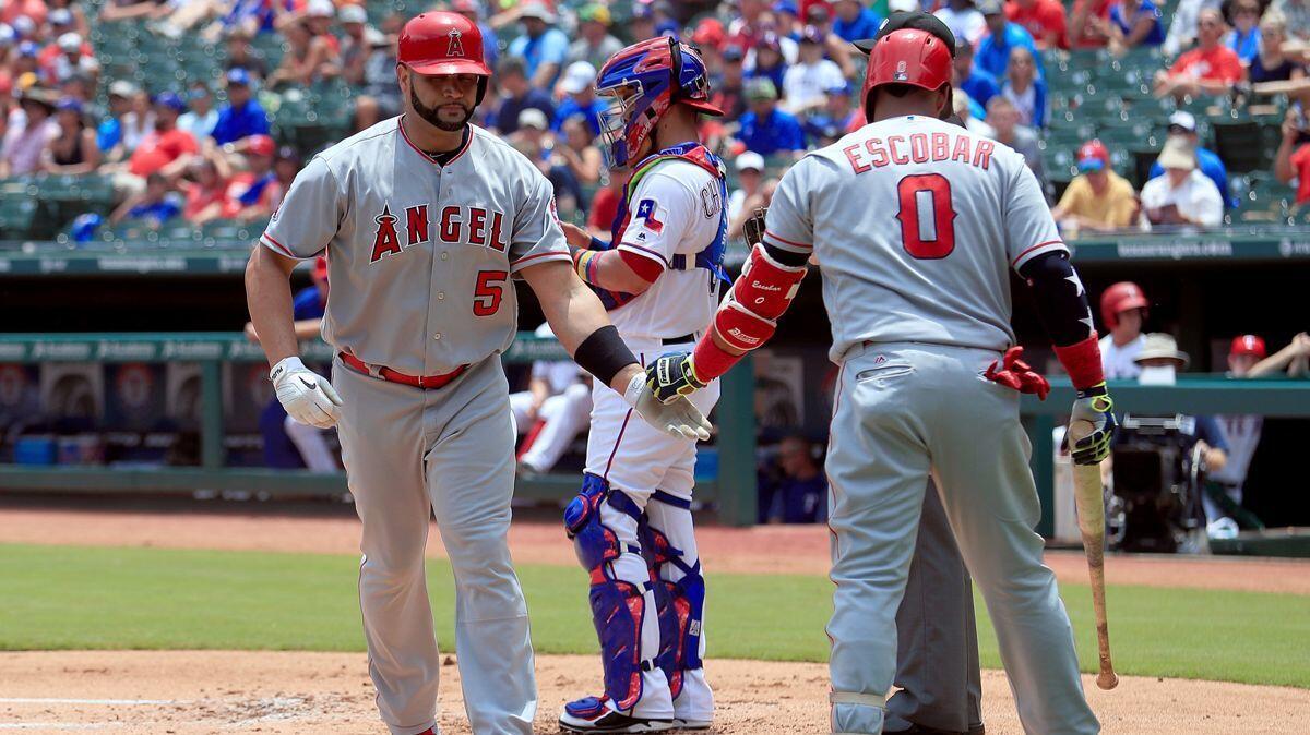 Angels' Albert Pujols, left, celebrates with Yunel Escobar after hitting a solo home run against the Texas Rangers in the top of the first inning on Sunday.