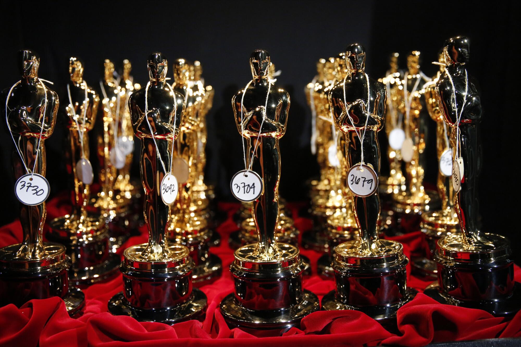 A bunch of Oscars trophies positioned on a red table