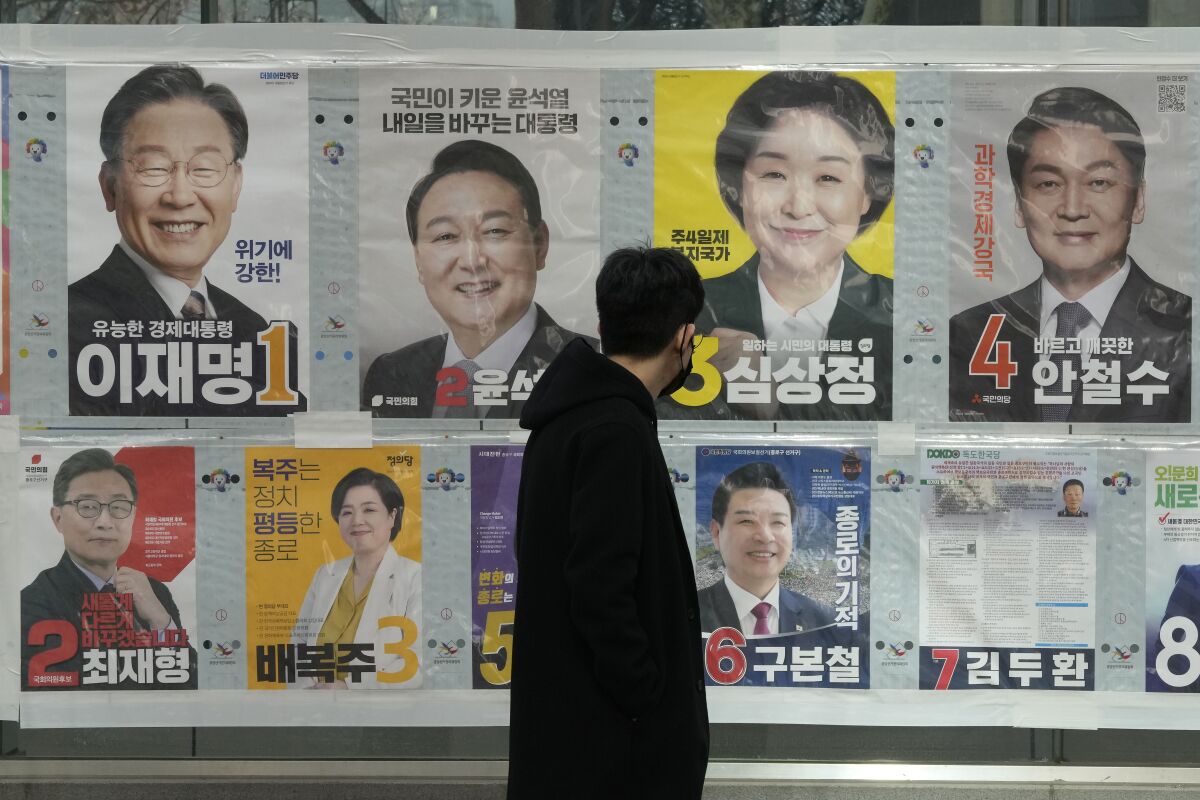 A man watches posters of presidential candidates on a street in Seoul, South Korea, March 3, 2022. Tens of millions of South Koreans are expected to vote Wednesday, March 9 to choose their new president. The winner will take office on May 10 for a single five-year term. Whoever wins, a new leader will be tasked with resolving various economic woes, easing threats from nuclear-armed North Korea and healing a nation sharply split along the lines of ideology, generation and gender. (AP Photo/Ahn Young-joon)