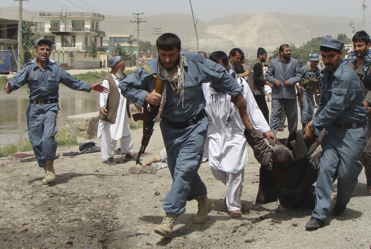 Afghan police officers evacuate a wounded person after a suicide bomber struck the offices of Mohammad Rasoul Mohseni, chief of the Baghlan provincial council, in Pul-e-Khumri.