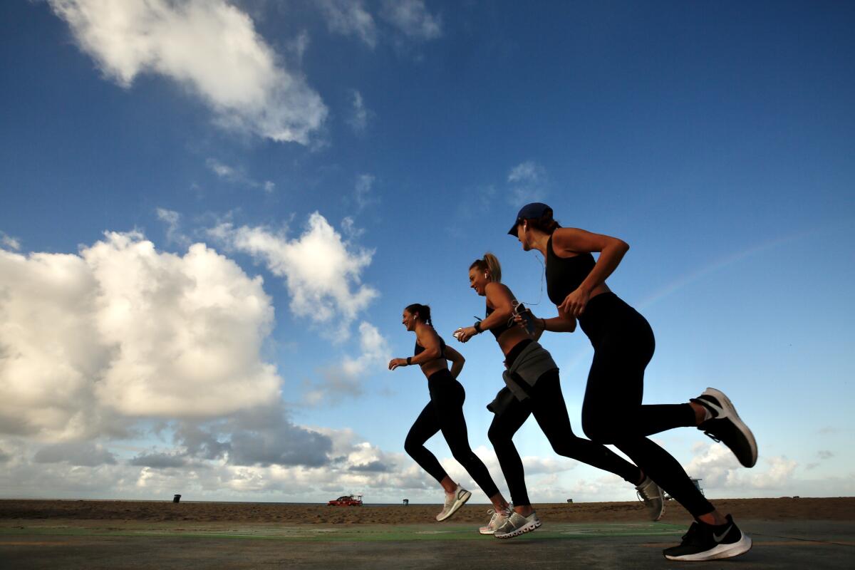 From left; Alysia Vickis, Casey Atamniuk and Courtney Olson, go for their daily morning run at Venice Beach on Monday, after a rain storm blew through the area.