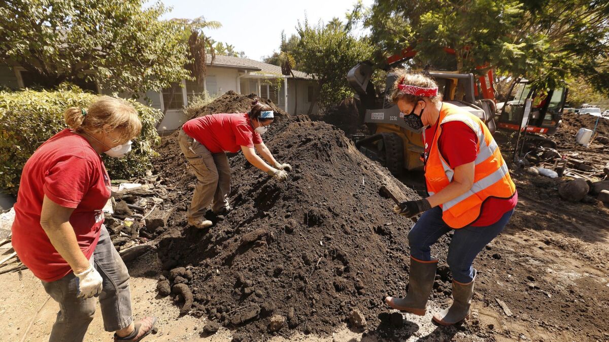Jennifer Stafford, left, Ana Fagan and Denise Walden — volunteers with the Santa Barbara Bucket Brigade — sort through a dirt pile in the yard of a home damaged in the Montecito mudslides.