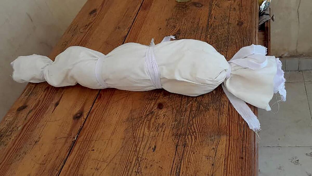 The body of a child is wrapped in white burial cloth in the Foster Home for Orphans in Khartoum, Sudan.