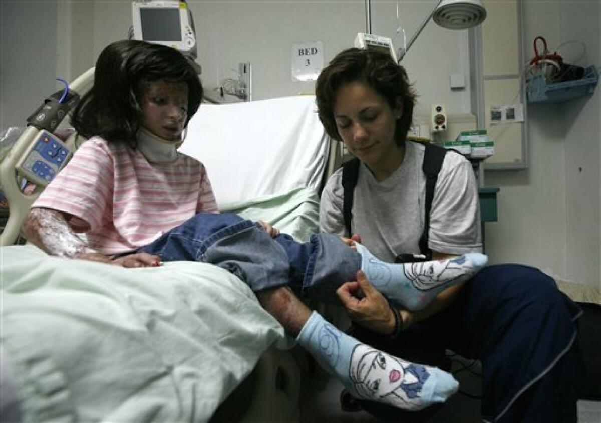 Capt. Christine Collins, of Miami, Ariz. dresses eight-year-old Razia before her departure from a U.S. military hospital in Bagram, Afghanistan, Wednesday, June 24, 2009. Razia, who was burned when a white phosphorus round hit her house during fighting between Taliban militants and U.S. and French troops in her village in the Tagab Valley on March 14, 2009, left the hospital after months of care and more than 15 surgeries. (AP Photo/Musadeq Sadeq)