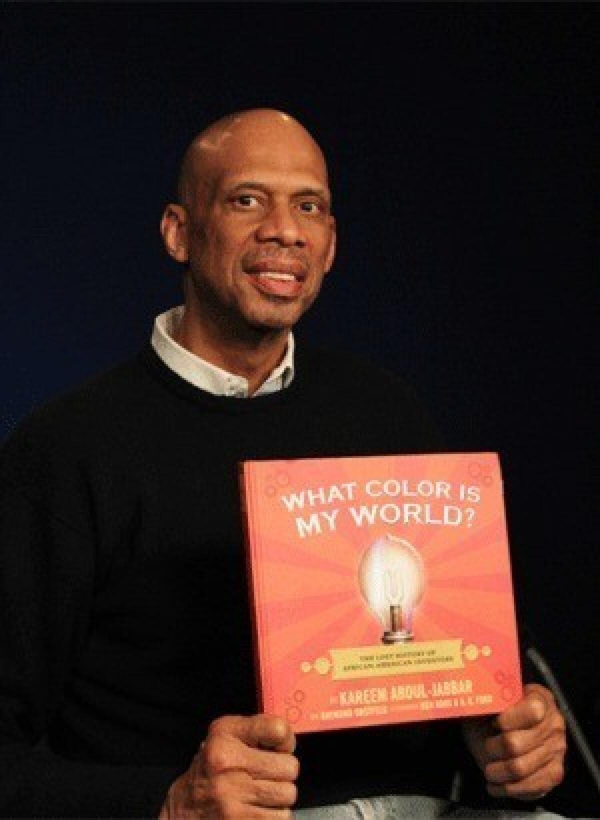 Former NBA player Kareem Abdul-Jabbar holds a copy of his new children's book, "What Color is My World?: The Lost History of African-American Inventors," in New York.
