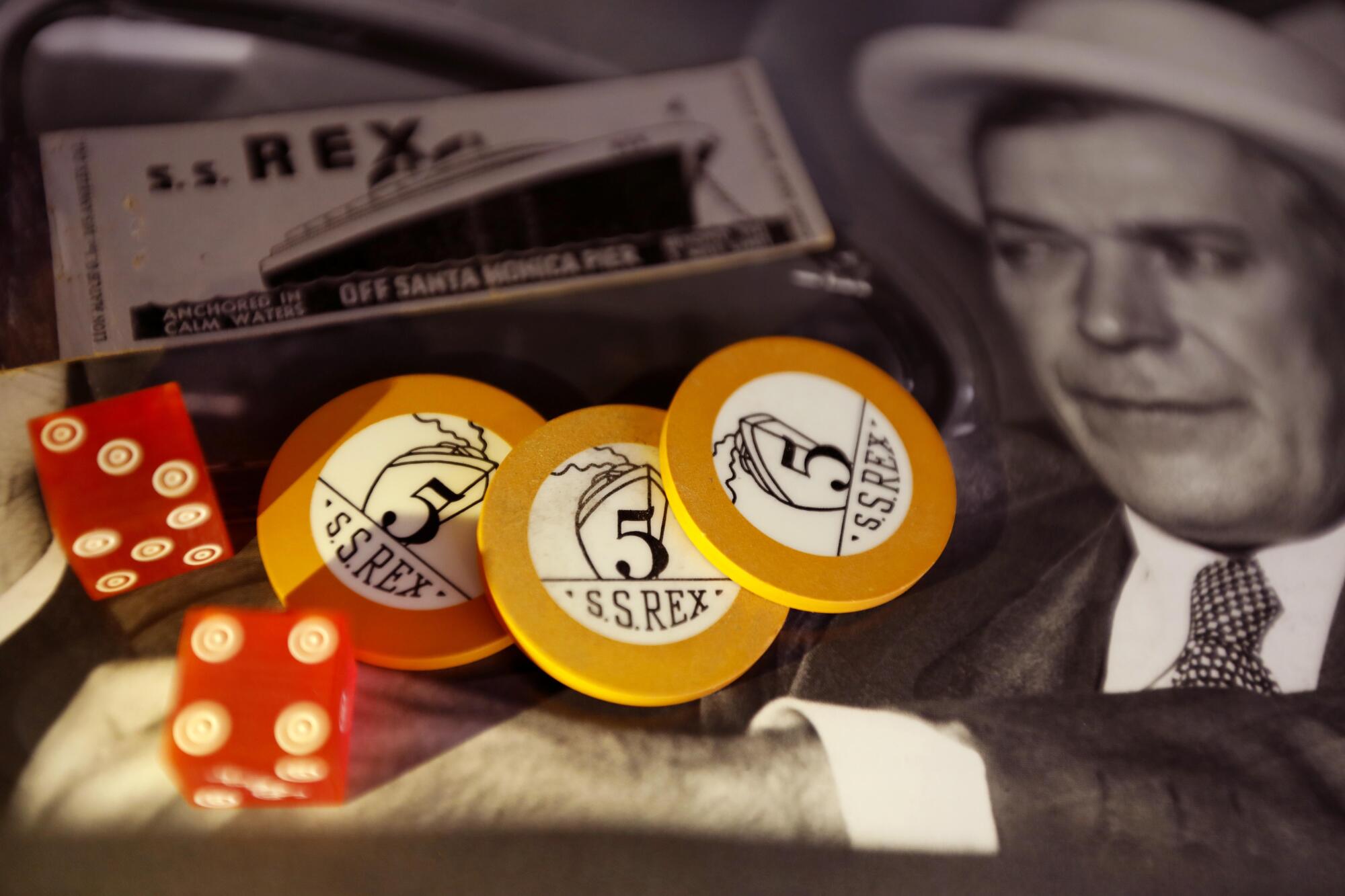 Artifacts from the S.S. Rex — gaming chips, dice and a matchbook — rest on a photograph of Tony Cornero.