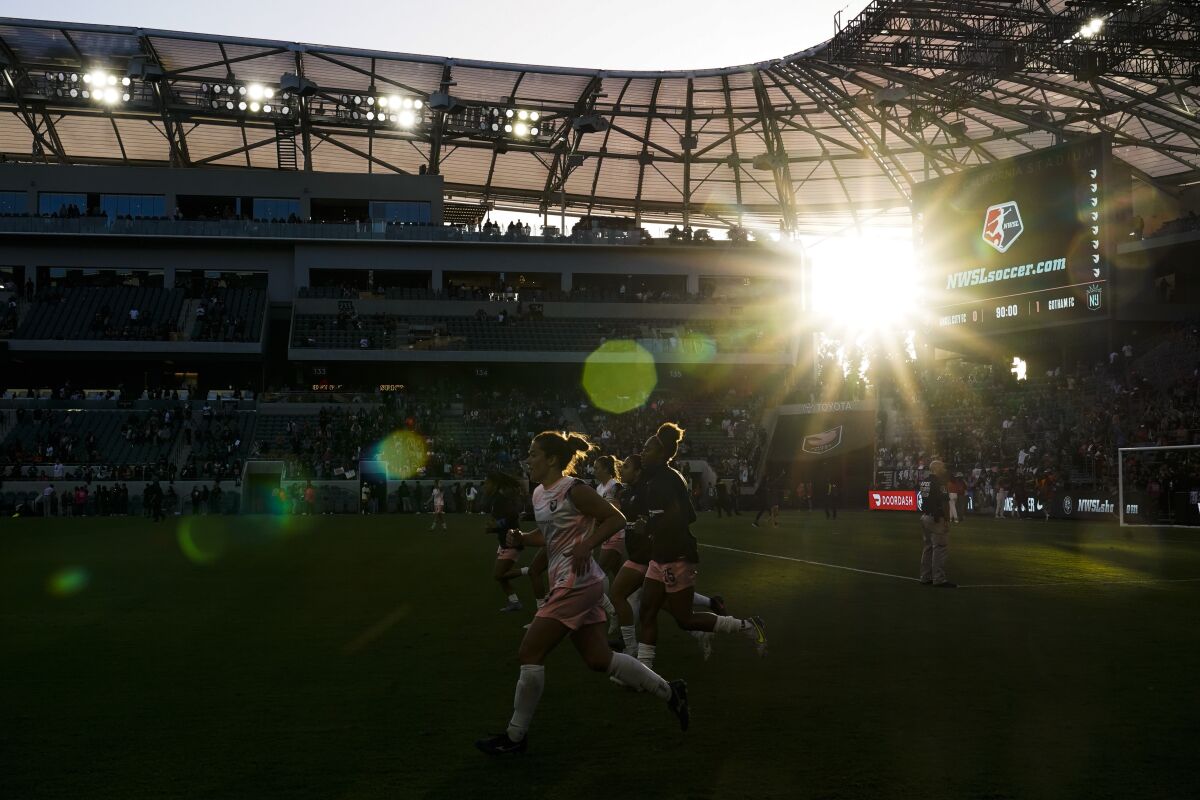 Angel City FC players run on the field after an NWSL soccer match at BMO Stadium in May 2022.