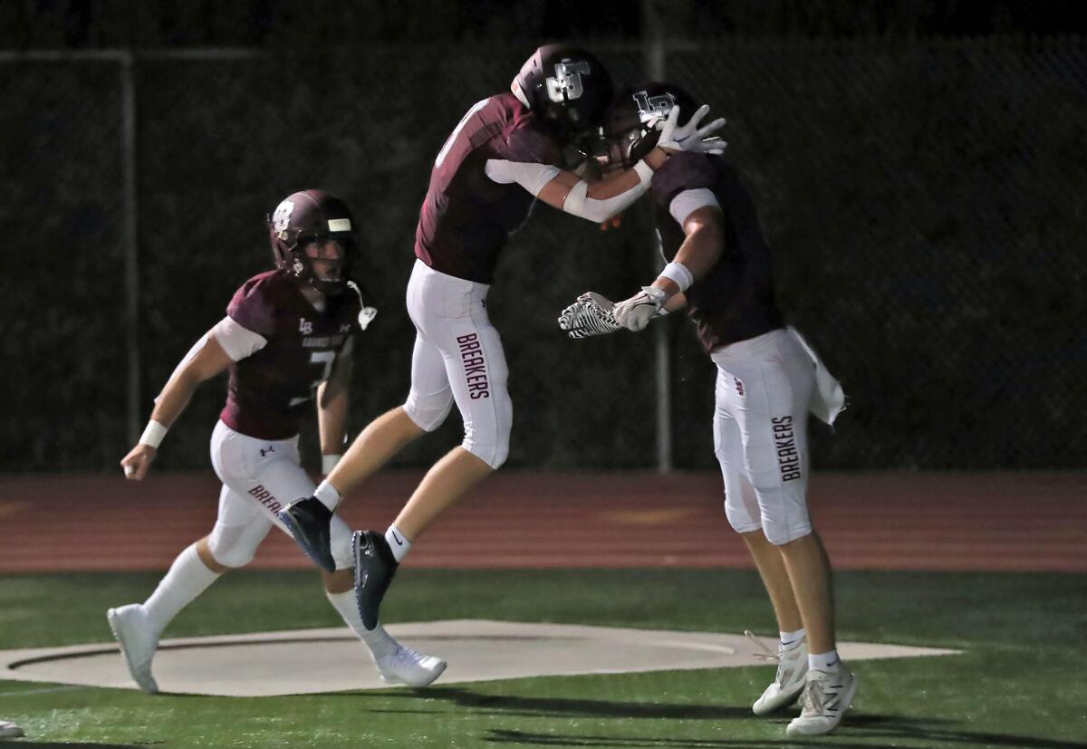 Wyatt Bogdan (17) from Laguna Beach, far right, is congratulated by teammates after scoring a pick-six interception.