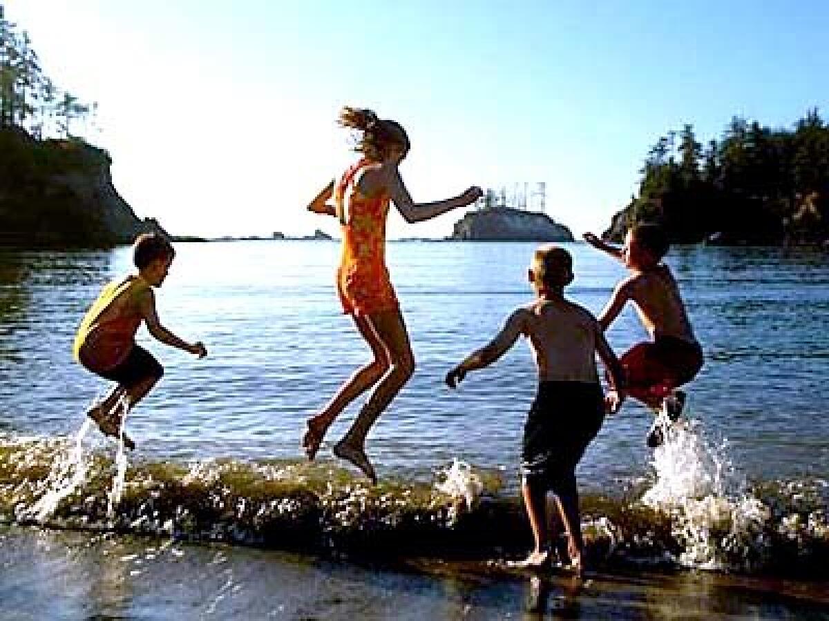 Young visitors jump the waves on the shore of Sunset Bay State Park, 12 miles southwest of Coos Bay in Oregon. Cape Arago Highway and hiking trails link Sunset Bay with two neighboring parks.