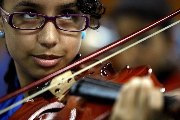 A young musician puts bow to strings in Caracas, Venezuela, where her classical music training comes compliments of El Sistema  the System. Today, about half a million young Venezuelans are enrolled in the programs centers. A shining alumnus: Gustavo Dudamel, music-director-to-be for the Los Angeles Philharmonic.
