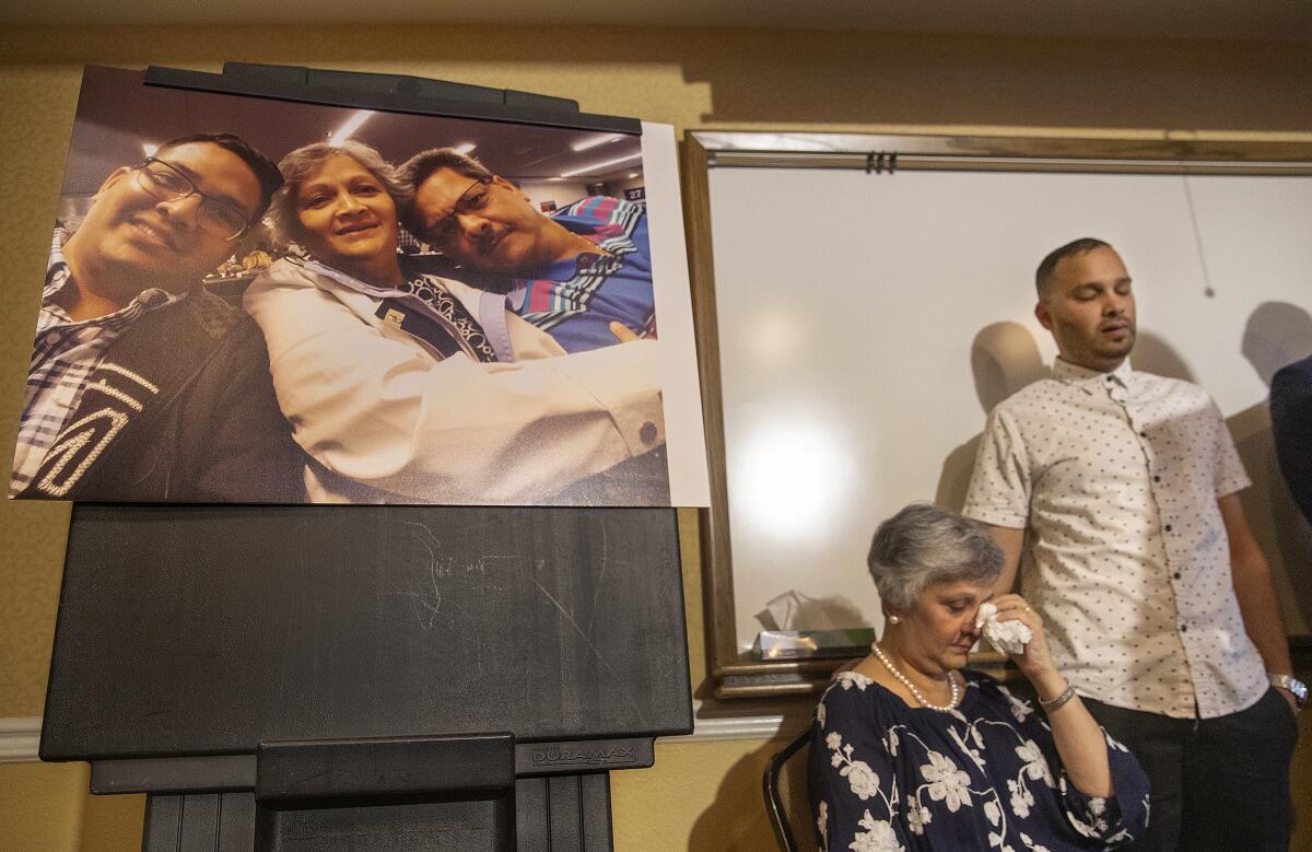 CORONA, CA-AUGUST 26, 2019: Paola French and her son Kevin react as Attorney Dale Galipo addresses the media during a press conference at the Ayres Hotel in Corona to announce plans to file a civil claim against the city of Los Angeles and LAPD officer Salvador Sanchez for the shooting death of Paolas son, Kenneth French inside a Corona Costco earlier this year. Photograph at left is of from left to right-Kenneth French and his parents, Paola, and Russell, taken in 2019. (Mel Melcon/Los Angeles Times)