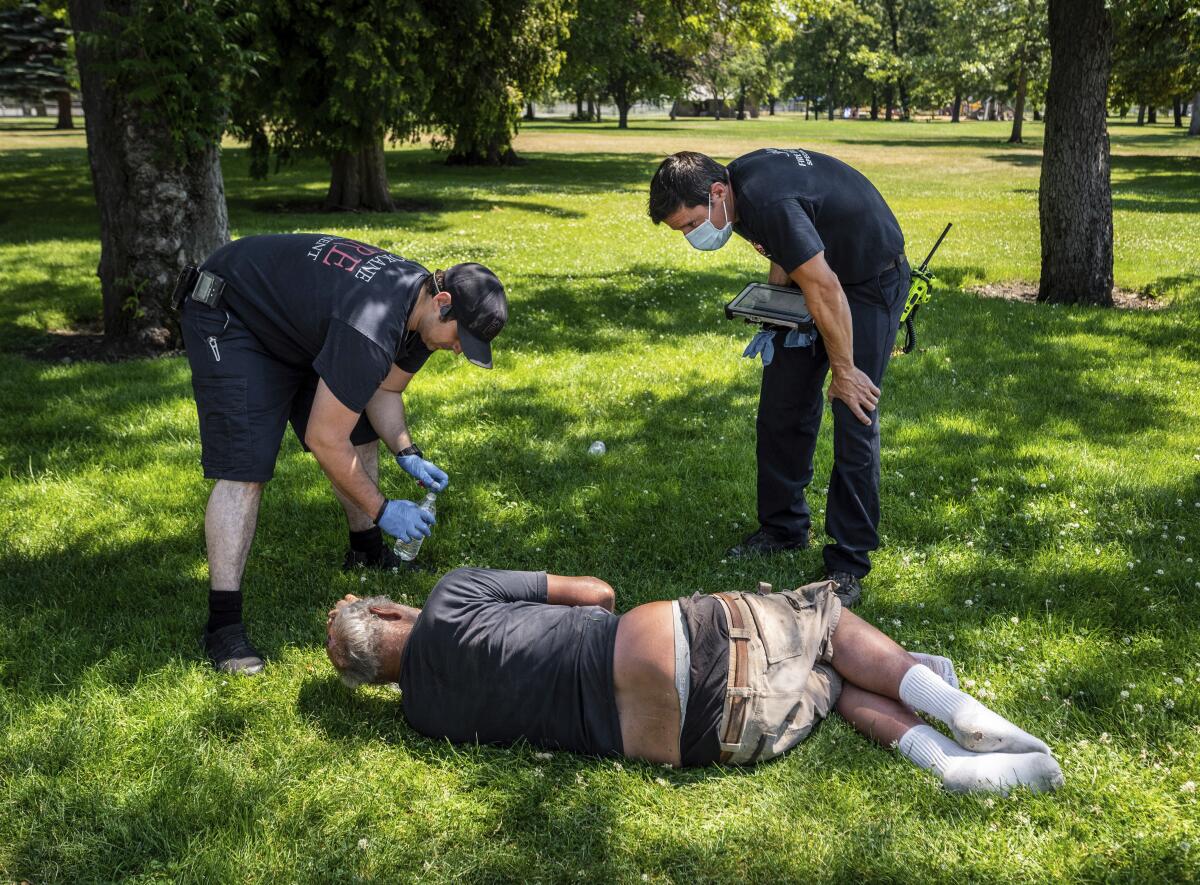 Firefighters check on the welfare of a man in Mission Park in Spokane, Washington