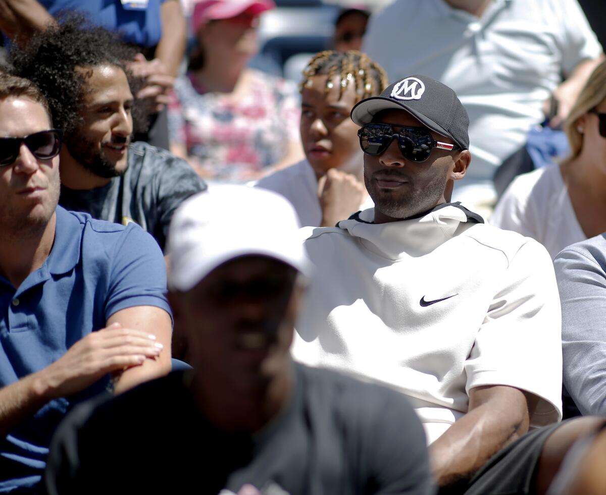 Kobe Bryant, right, and Colin Kaepernick, second from left, watch the second round of the U.S. Open on Thursday.
