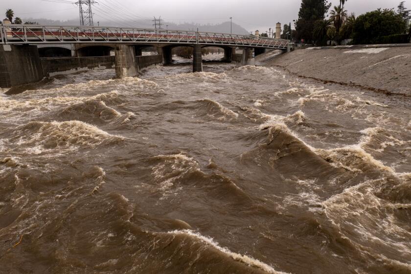 LOS ANGELES, CA - JANUARY 05: In an aerial view, the Los Angeles River flows at a powerful rate as a huge storm slams into the West Coast on January 5, 2023 in Los Angeles, California. California is being inundated by a "Pineapple Express" storm, or atmospheric river, and a bomb cyclone, a rapidly rotating storm system, bringing heavy rain and wind, and the threat of widespread flooding and possible landslides near wildfire burn areas. Coastal areas may sustain damage and heavy snow is accumulating the mountains. The dangerous storm condition has prompted California Gov. Gavin Newsom to declare a state of emergency. (Photo by David McNew/Getty Images)