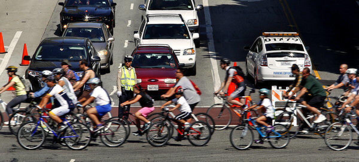 Cars wait at a traffic light as CicLAvia participants pass on Main Street in downtown Los Angeles.