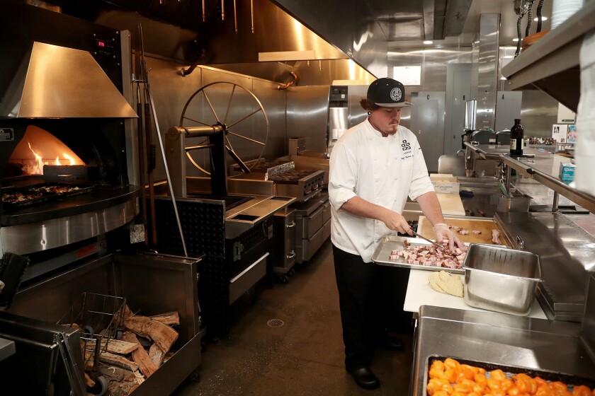 Lead chef Trevor Moak chops up pork lardon that will be used for an arugula salad at Chaak Kitchen in Tustin.