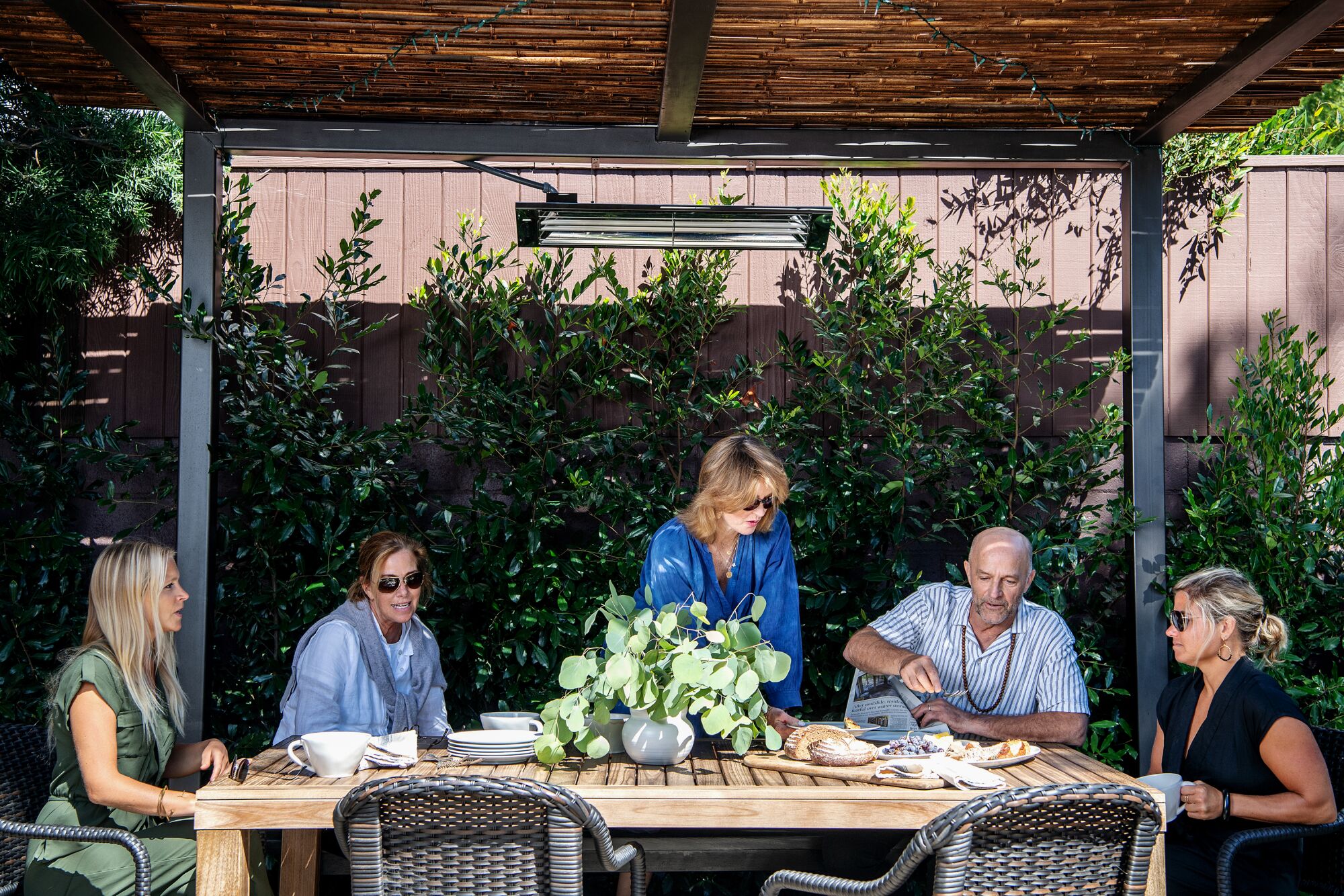 A group of people sit at an outdoor dining table 