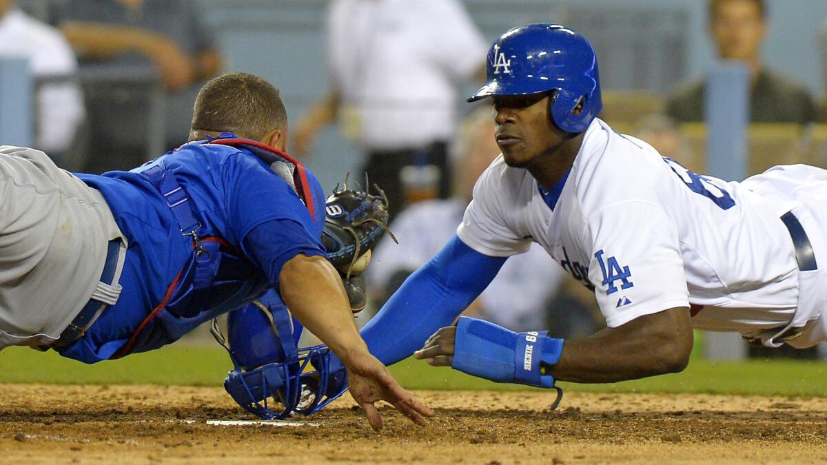 Dodgers baserunner Yasiel Puig, right, avoids the tag of Chicago Cubs catcher Welington Castillo to score in the sixth inning of the Dodgers' 8-2 loss Friday.