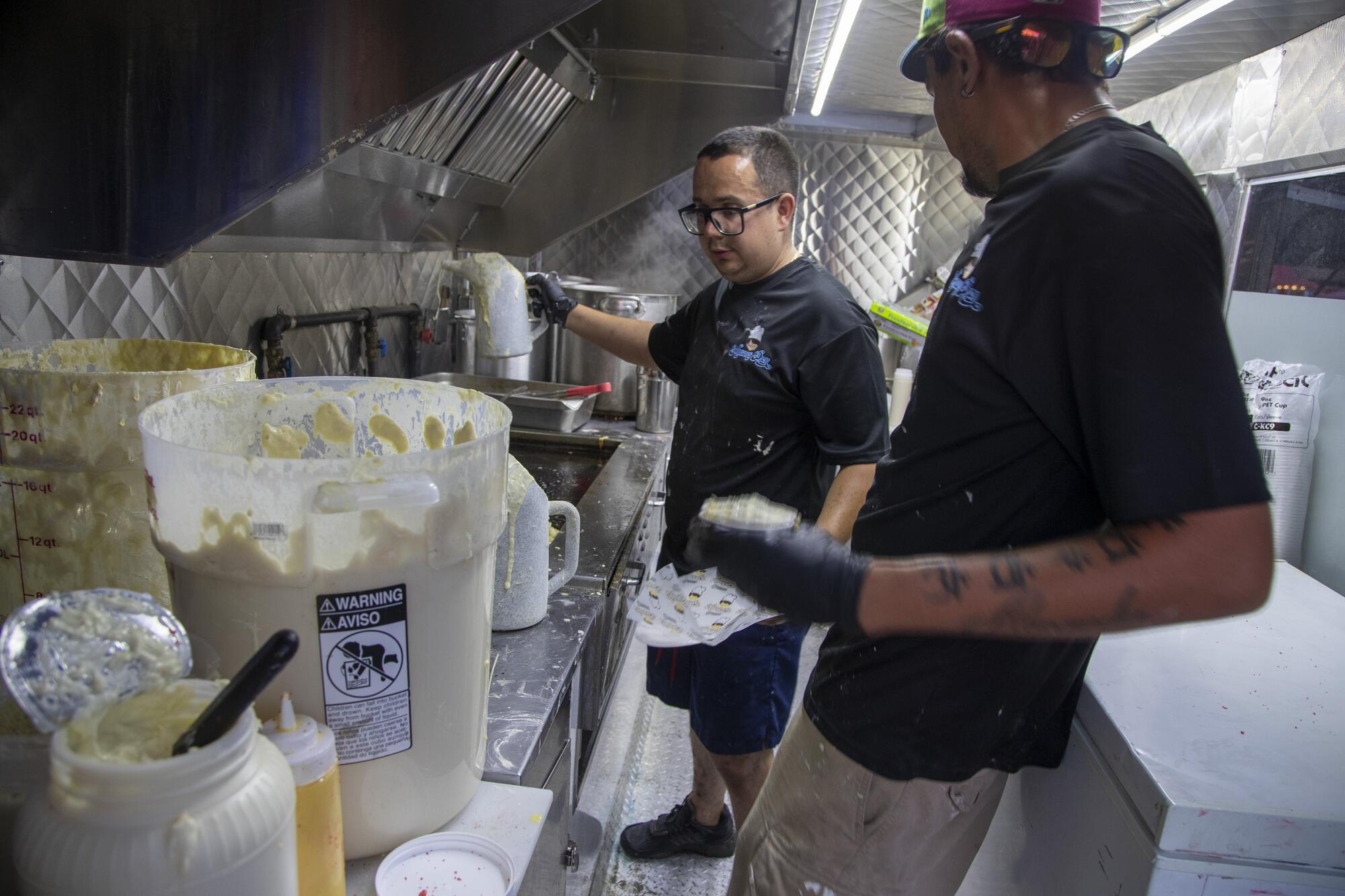 Mason's Den owner German Arteaga, left, makes funnel cakes and grilled corn 