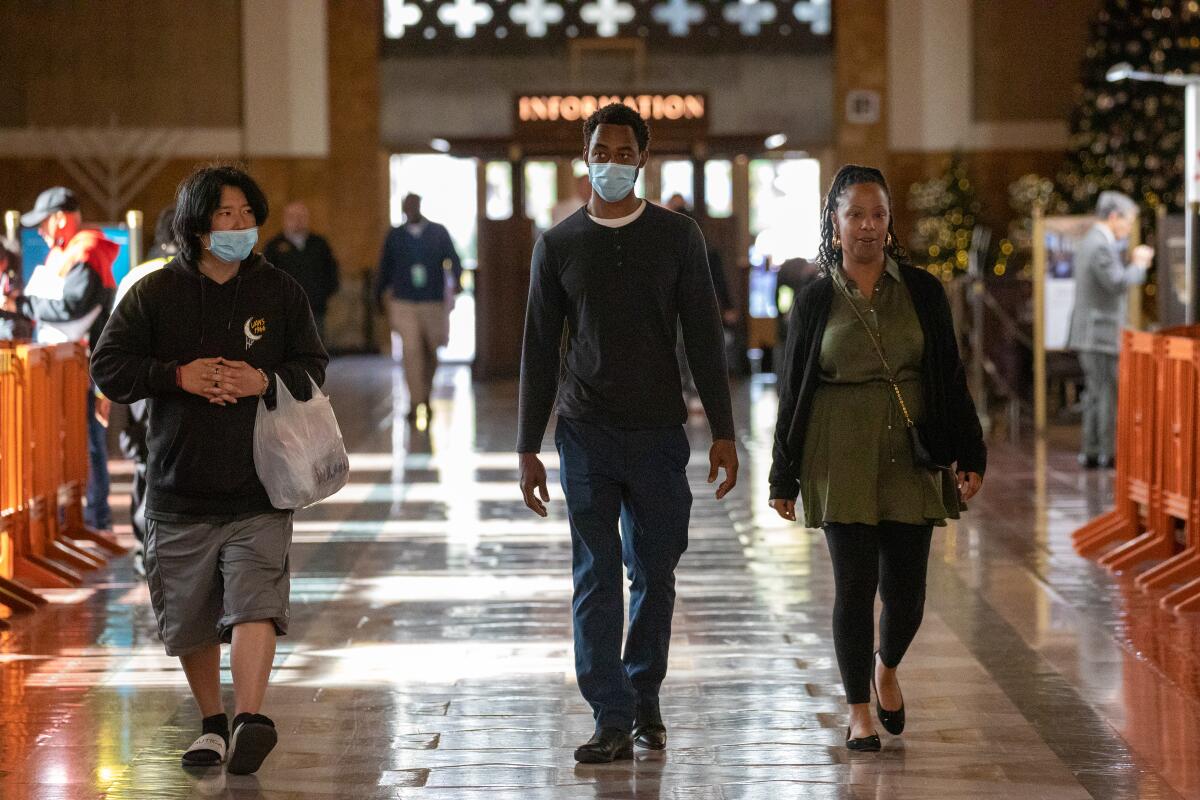 Commuters with and without masks walk through Los Angeles Union Station