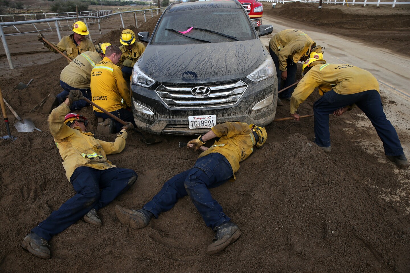 An L.A. County fire crew digs a car out of the mud covering Lake Elizabeth Road where its owner, Esther Shelton of Palmdale, abandoned it.