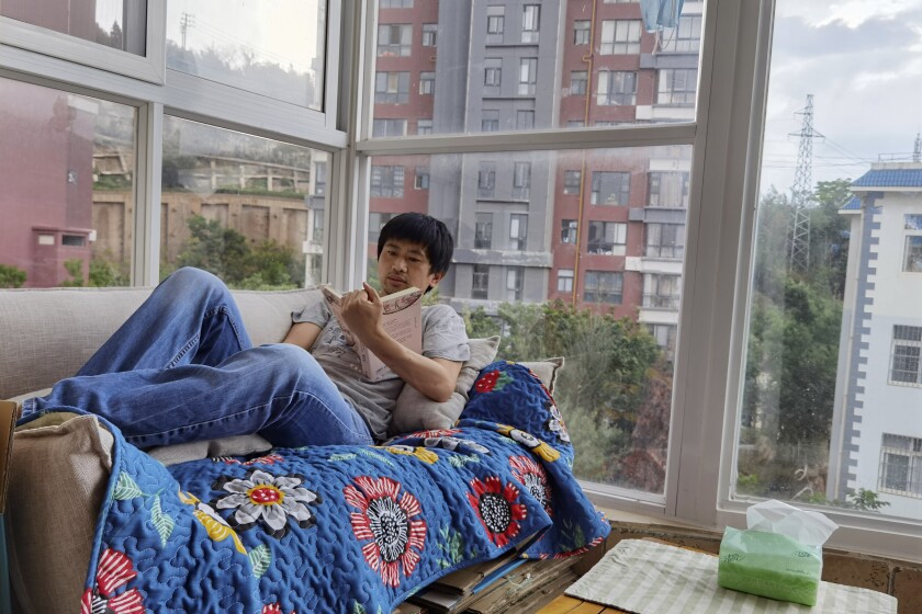 Guo Jianlong reads a book on the balcony of his home in Dali in southwestern China's Yunnan province