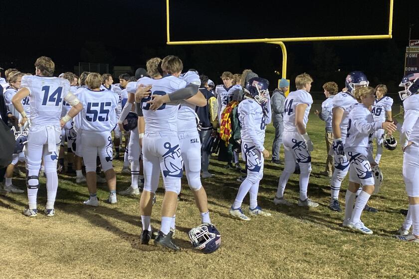 Newport Harbor players embrace after suffering a 58-17 loss to Highland in a CIF Southern Section Division 9 semifinal game on Friday in Palmdale.