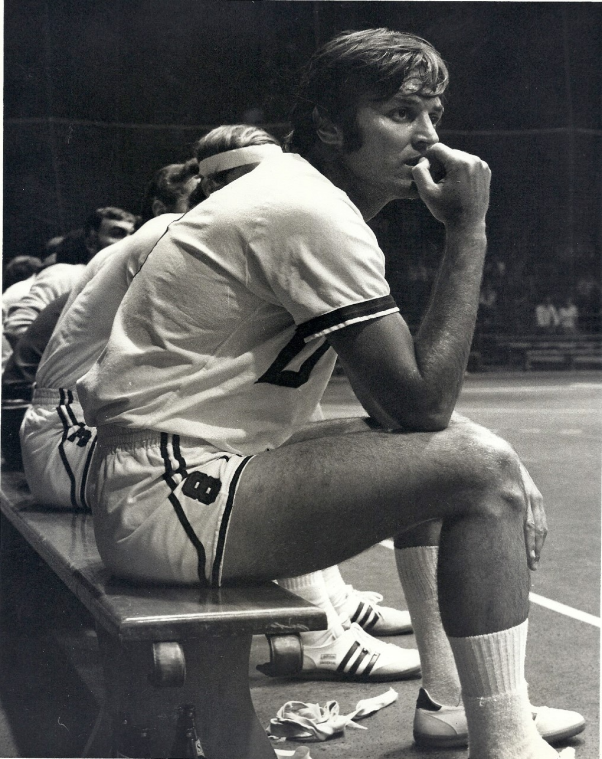 Dennis Berkholtz sits on the sidelines at a handball game in a black-and-white photo.