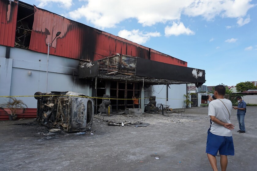 A man stands outside of a torched nightclub after two groups clashed in Sorong, West Papua province, Indonesia, Tuesday, Jan. 25, 2022. A fire engulfed the nightclub after two groups clashed inside the building and 19 people were killed, officials said Tuesday. (AP Photo)