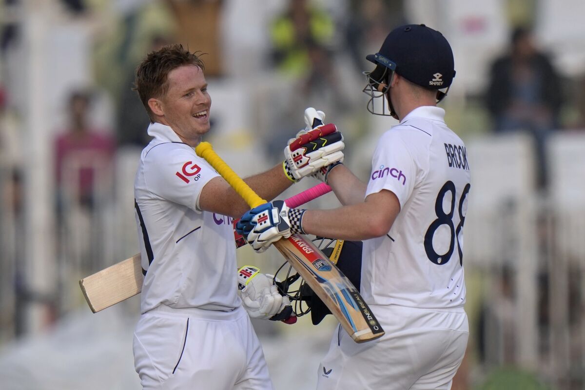England's Ollie Pope, left, celebrates with teammate Harry Brook after scoring century during the first day of the first test cricket match between Pakistan and England, in Rawalpindi, Pakistan, Dec. 1, 2022. (AP Photo/Anjum Naveed)