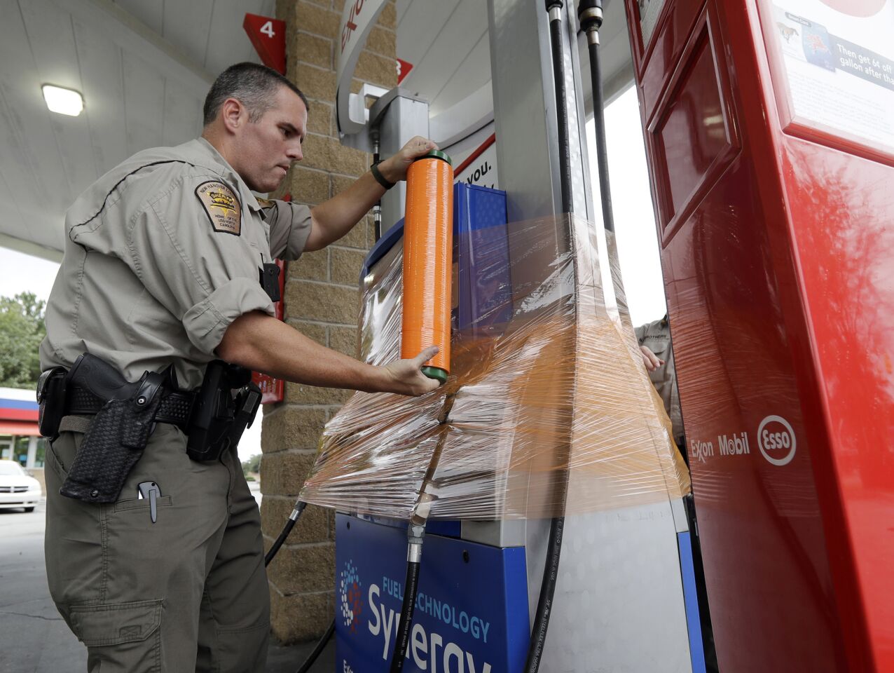 New Hanover Sheriff's deputy J. Brown wraps a gas pump for protection in Wilmington, N.C., as Hurricane Florence threatens the coast Thursday,