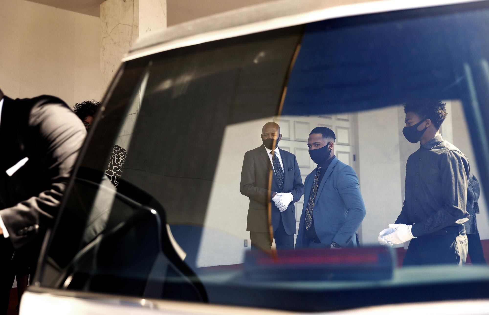 Family members watch as Charles Jackson's coffin is placed inside a hearse.