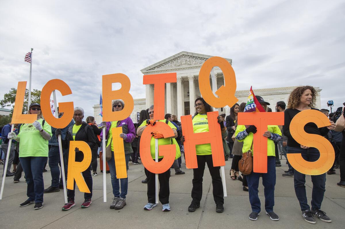 Supporters hold letters that spell "LGBTQ rights" outside the U.S. Supreme Court.