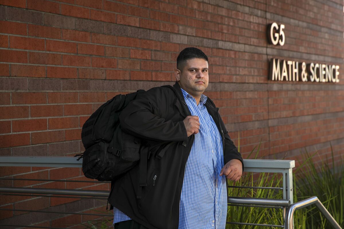 A young man leans against a rail outside a building at East L.A. Community College.