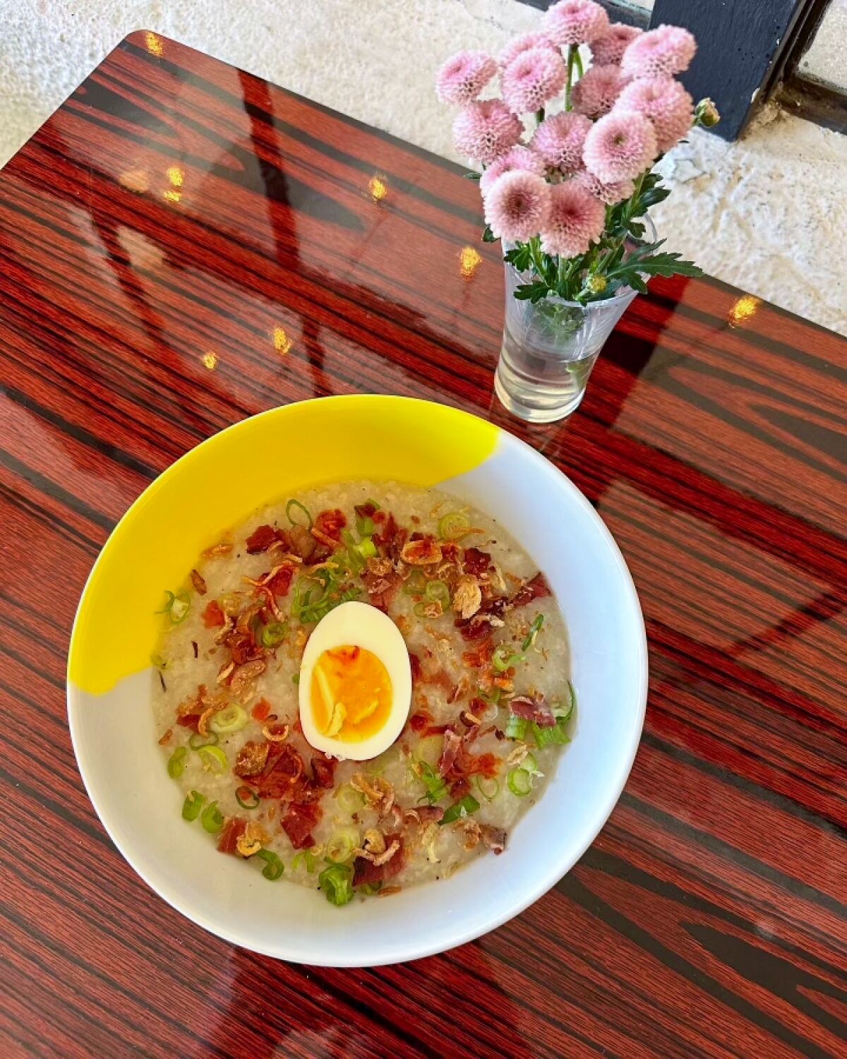 An overhead vertical photo of a bowl of Filipino chicken congee at Arroz and Fun