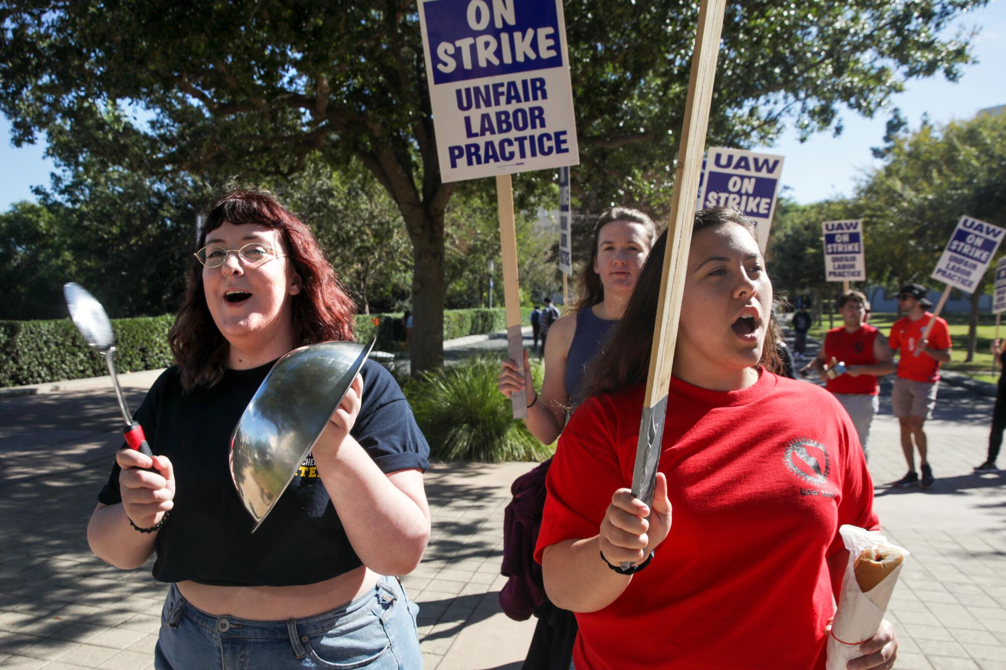 Two young women lead a group of protesters demanding better pay and benefits at a UWA rally at UC Irvine.