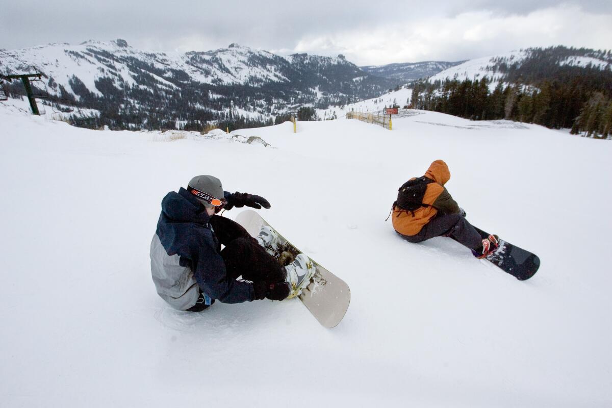 A pair of snowboarders going down a hill.