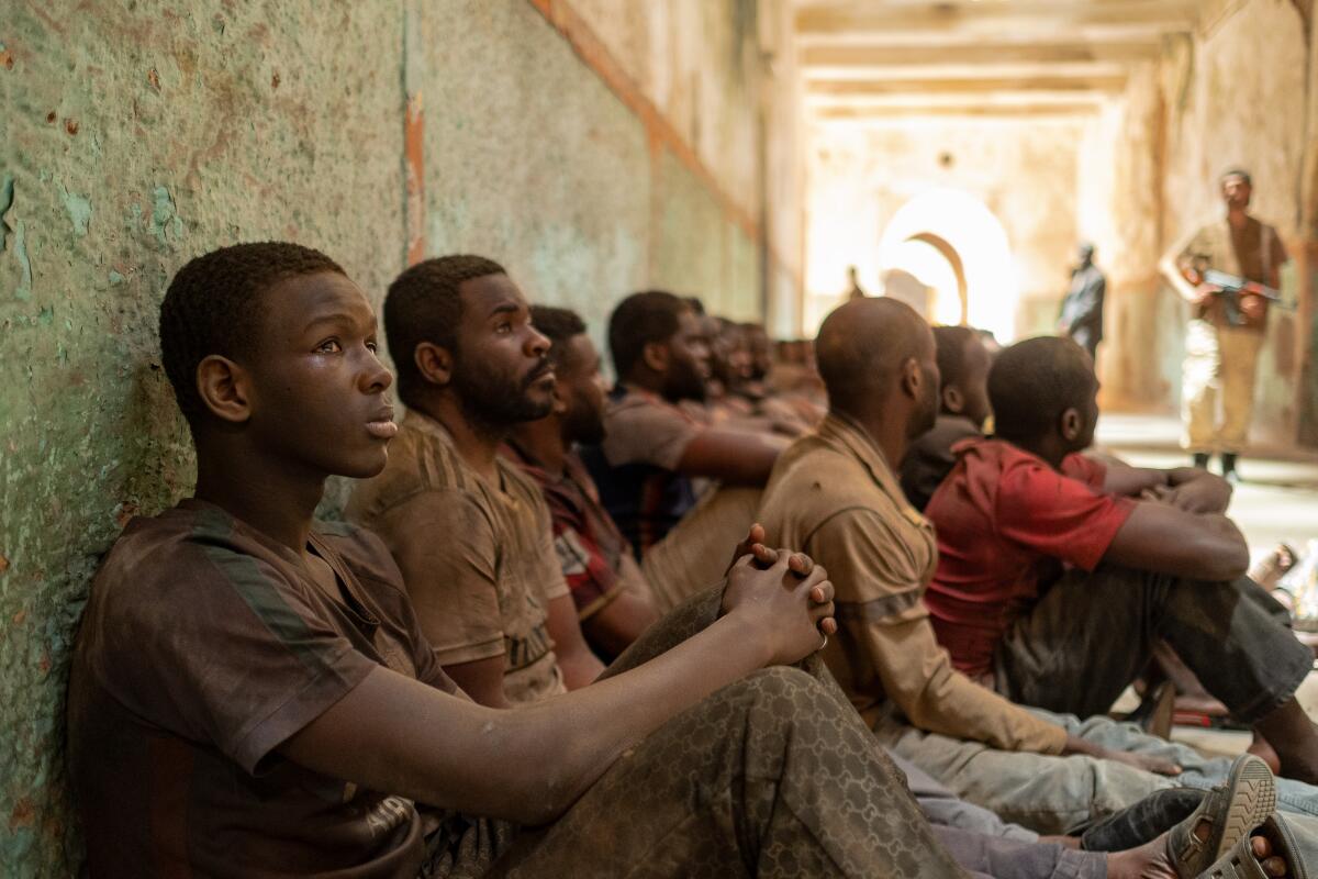 A young man sits in a group of detainees.