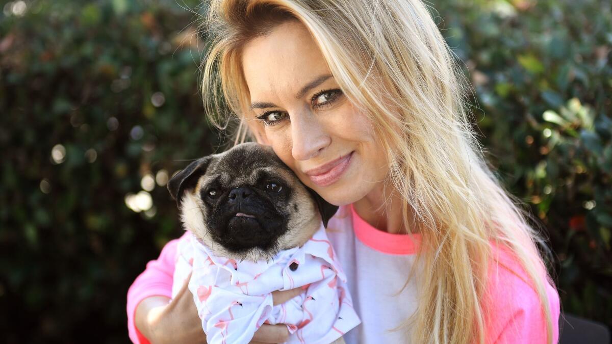 Izabella St. James, known on social media as The Pug Queen, hugs Chance, a pug she rescued from Iran.