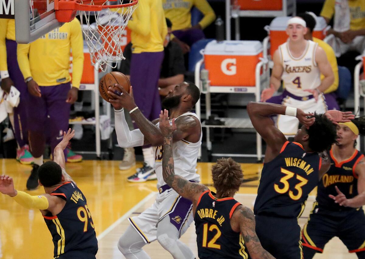 Lakers star LeBron James, center, is fouled by Golden State's Kelly Oubre Jr. while driving to the basket.