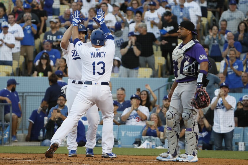 Colorado Rockies catcher Elias Diaz watches as Will Smith and Max Munsey of the Dodgers celebrate victory.