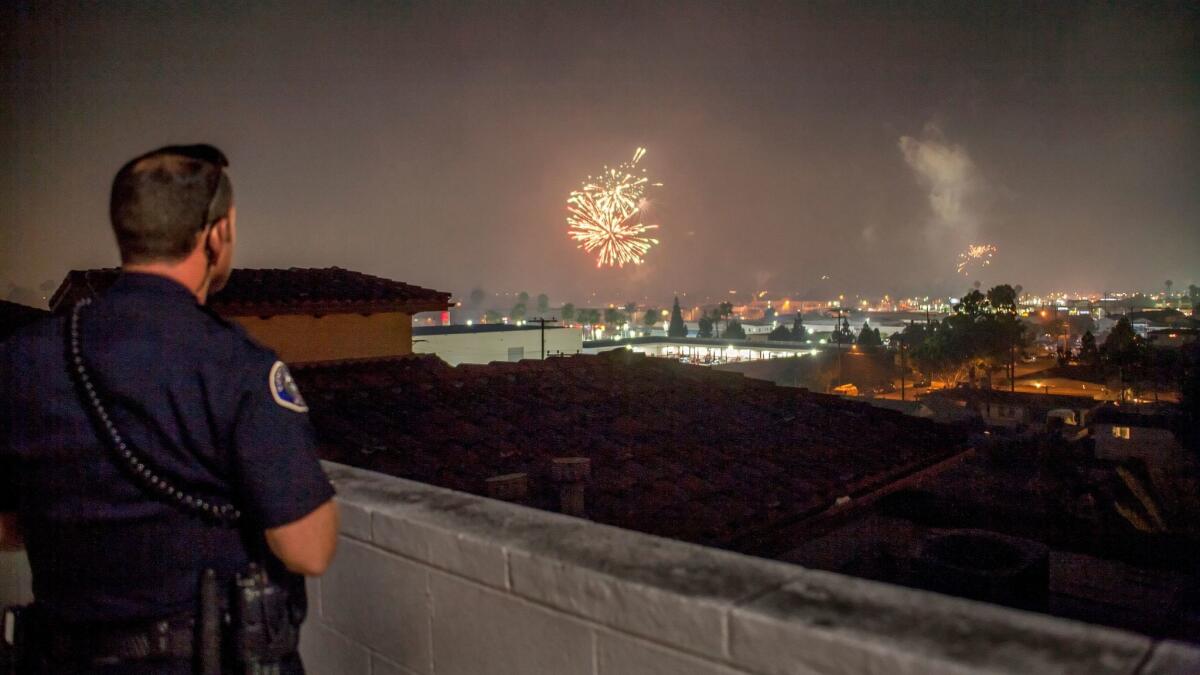 From the roof of a parking garage next to the Triangle Square entertainment center, Officer Trevor Jones scans Costa Mesa for illegal fireworks the evening of July 4.