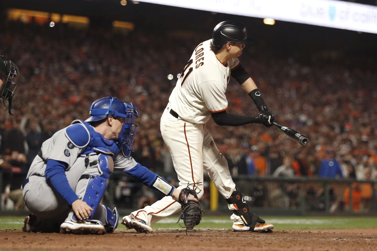 San Francisco Giants' Wilmer Flores is called out swinging in front of Dodgers catcher Will Smith.
