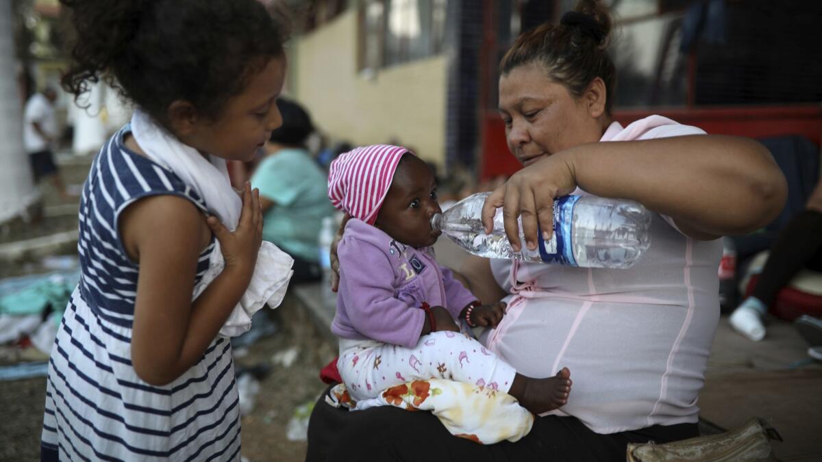 A Central American woman gives water to a baby as a large group of immigrants sets up camp for a few days at a sports center in Matias Romero in Mexico's Oaxaca state late Monday.