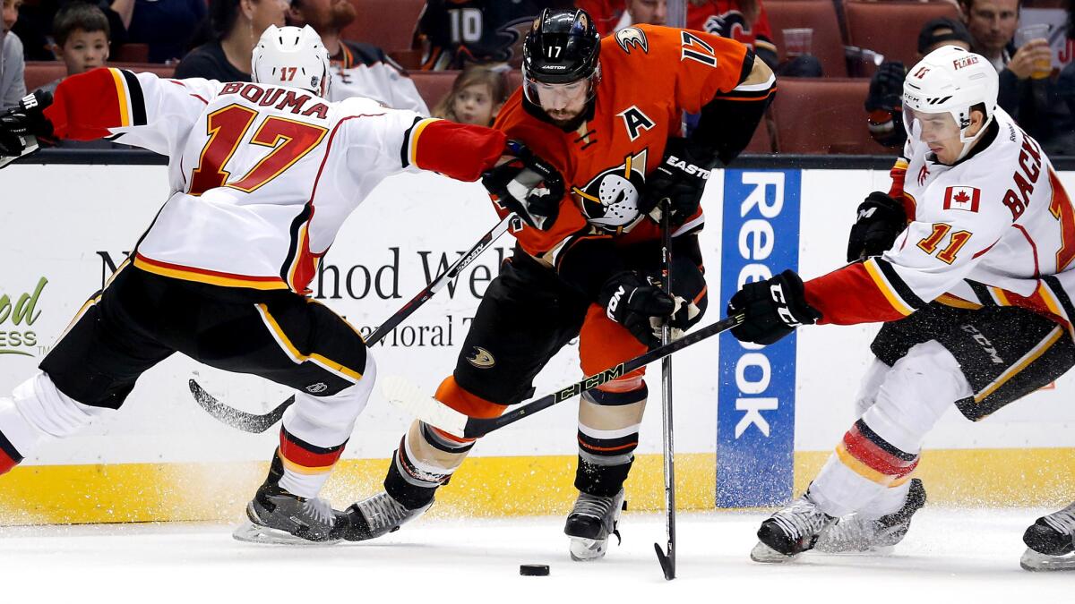 Ducks center Ryan Kesler splits the defense of Calcary's Mikael Backlund (11) and Lance Bouma during their game Sunday night in Anaheim.