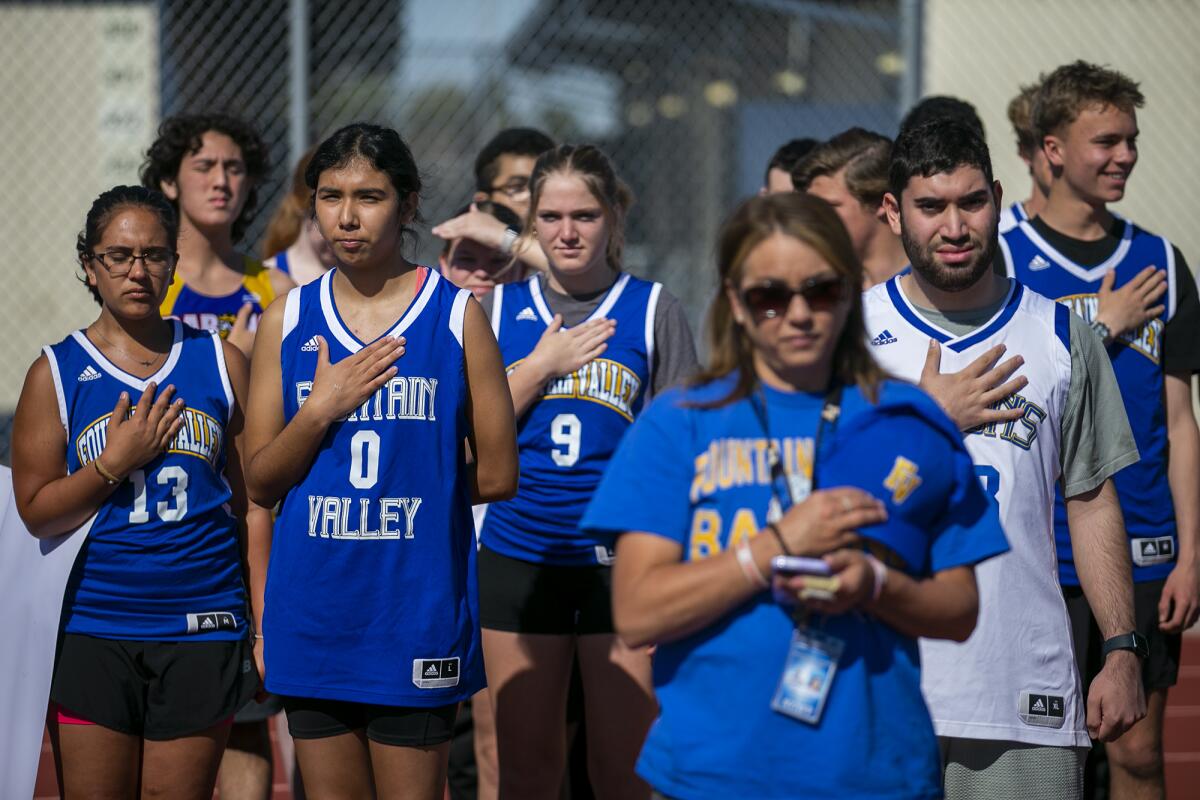 Fountain Valley High School's delegation stands for the National Anthem during Thursday's track meet.