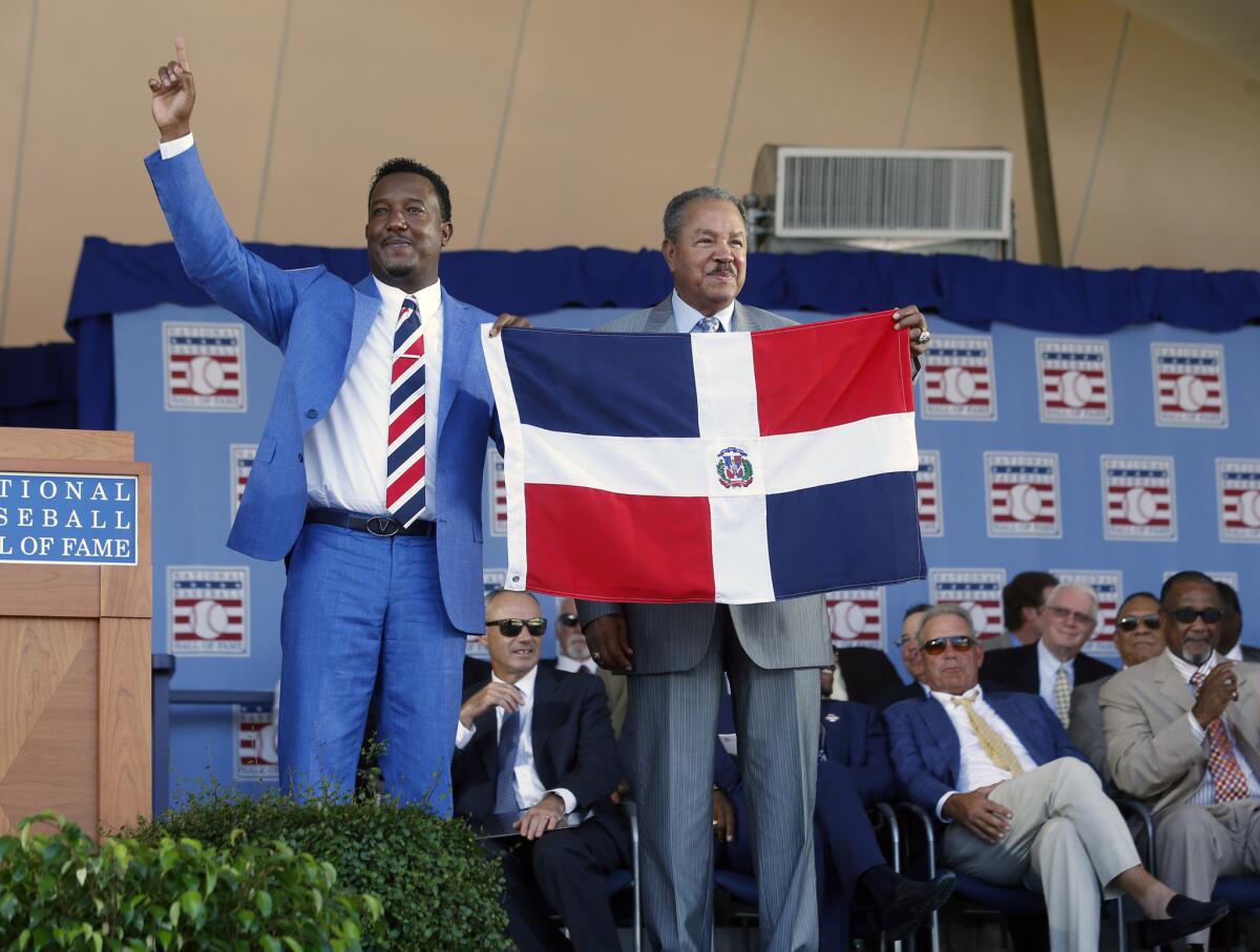 Los miembros del Salón de la Fama, Pedro Martínez, izquierda, y Juan Marichal, posan con una bandera de República Dominicana el domingo, 26 de julio de 2015, durante la ceremonia de exaltación de Martínez en Cooperstown, Nueva York.