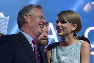 Scott Swift and his daughter Taylor Swift wear formalwear while smiling at each other onstage