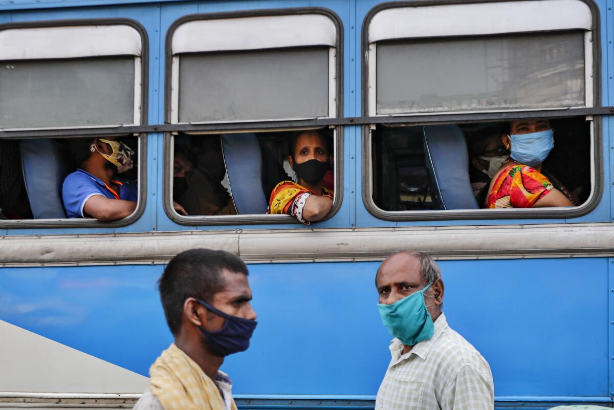 Commuters in a bus and pedestrians on the street wear masks in Kolkata, India.